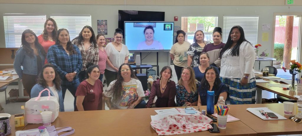 A group of 18 local people, most Indigenous People, stand and sit together around the trainer on a large screen who taught via Zoom. And the Mendocino Doula community grows with Indigenous Doulas.